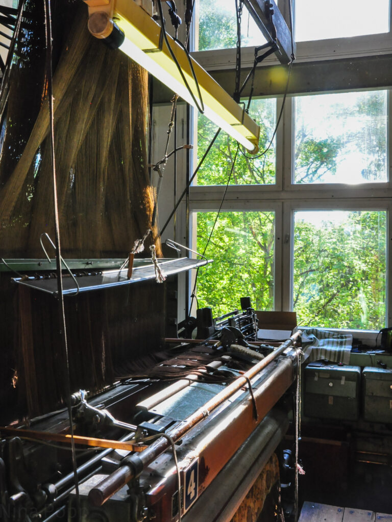 Ein historischer Webstuhl wird von einer Leuchtstoffröhre beleuchtet.